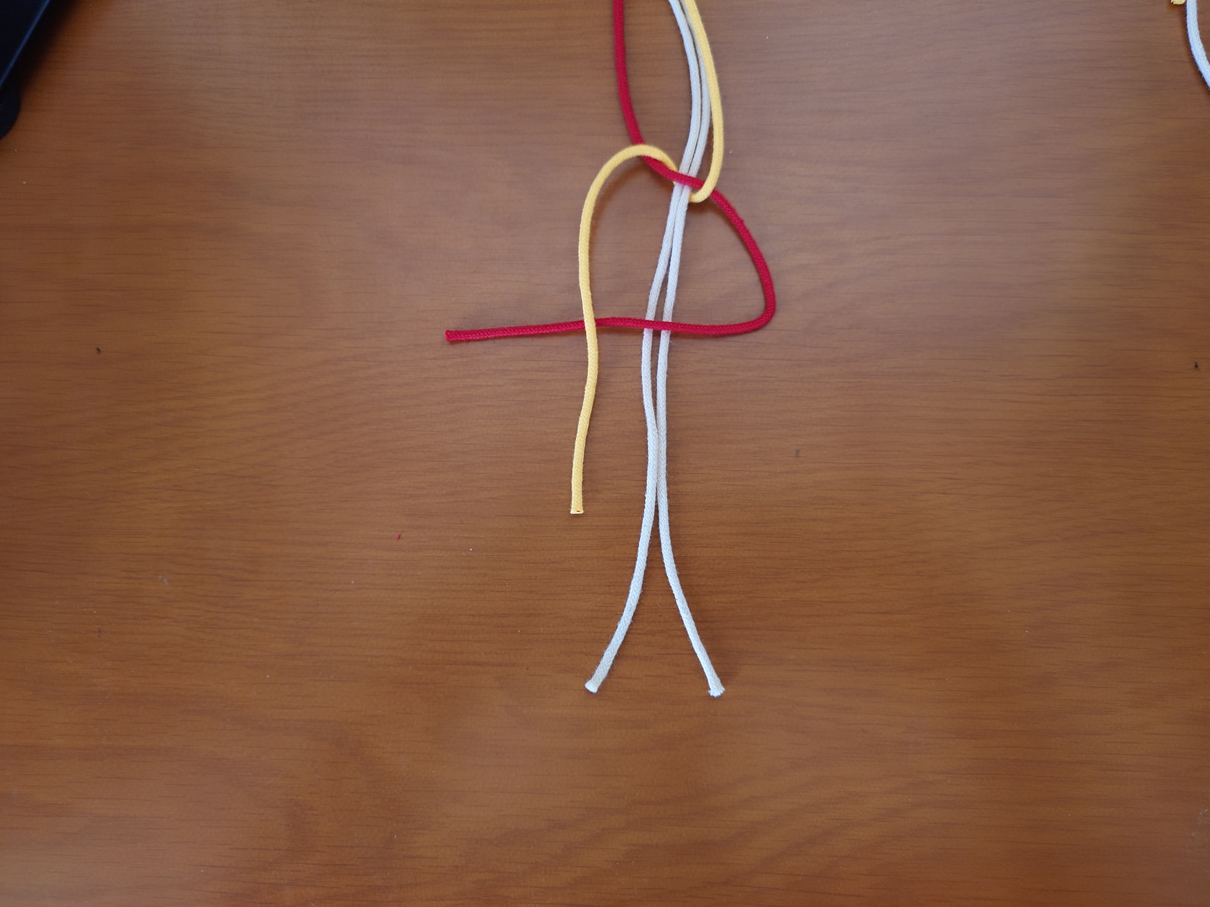 右端の紐を三角に置き、左端の紐をその上に置く