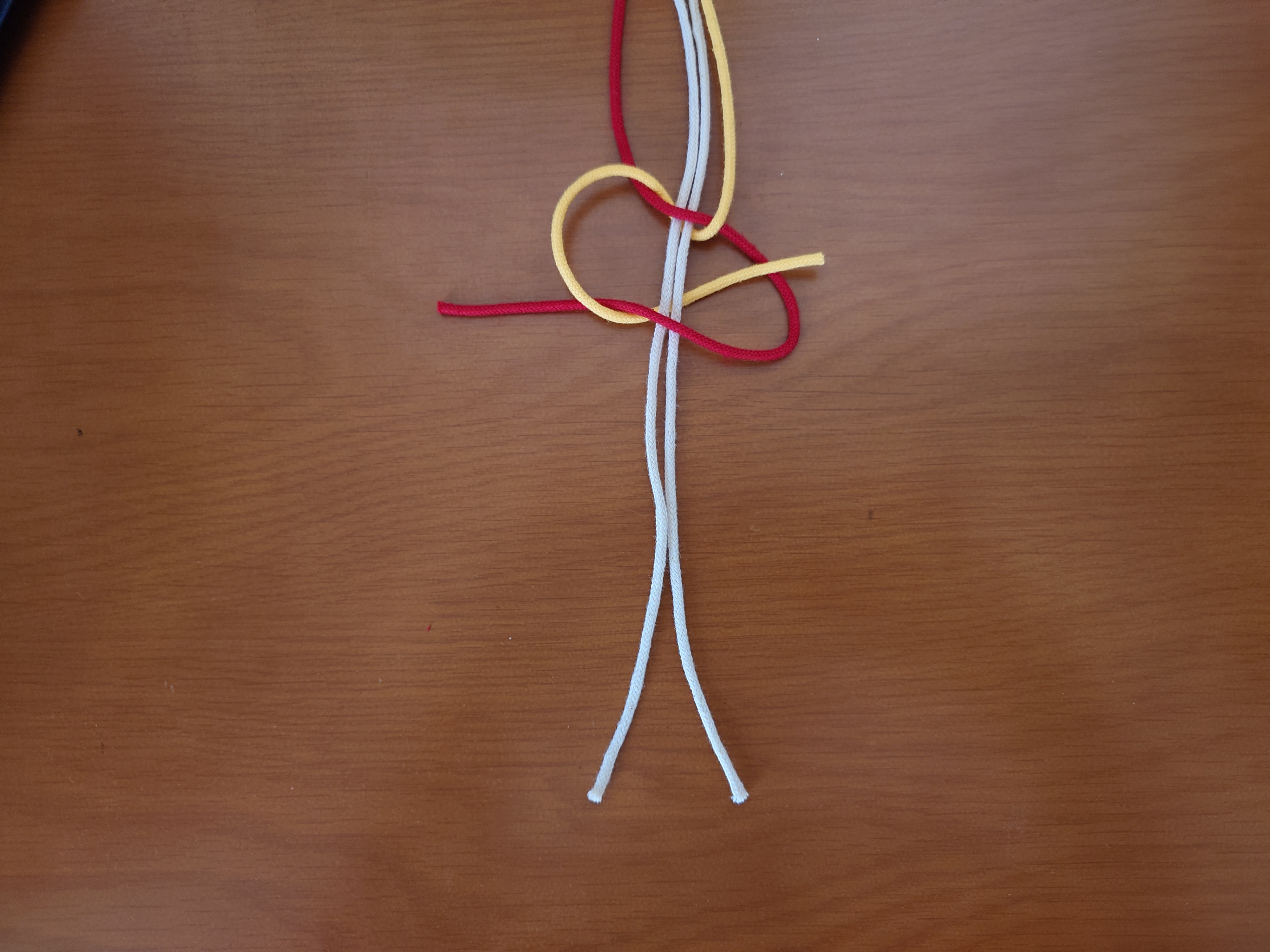 左端の紐を、その他の全ての紐の裏側から通して、三角の中から出す